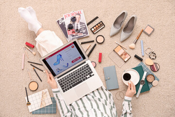Woman with cup of coffee, laptop and accessories shopping online on beige carpet