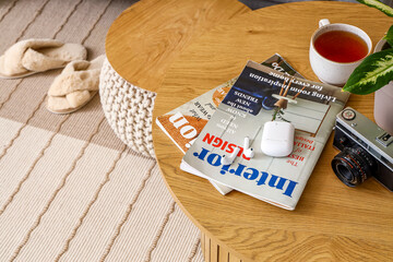 Coffee table with magazines, cup of tea, camera and earphones in interior of living room