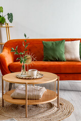 Coffee table with cup of tea, vase and mirror in interior of living room