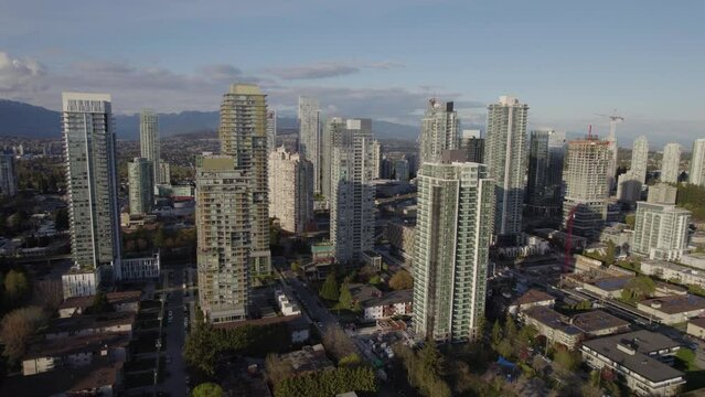 Aerial pan around tall skyscrapers with mountains in the background near Vancouver, BC