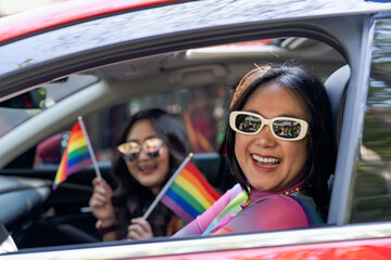 Happy Asian woman support LGBT pride parade in car. with Rainbow of LGBTQ or LGBTQIA 