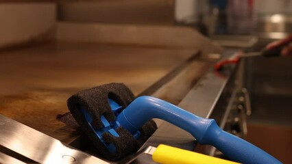 Restaurant Chef Cleaning Grill Surface In Kitchen.