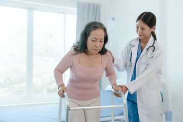 Asian Chinese female physiotherapist caregiver helping elderly woman exercise for recovery, prevention of osteoarthritis and osteoporosis.