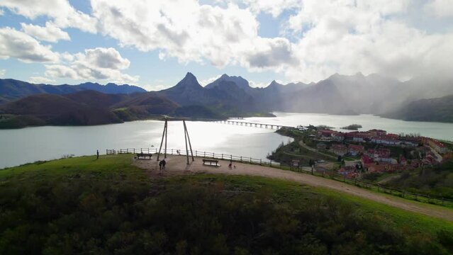 Parents swinging their child on the swing at the viewpoint in Ria&ntilde;o, a village in Le&oacute;n, Spain on the shore of a large reservoir in the Cantabrian mountains.