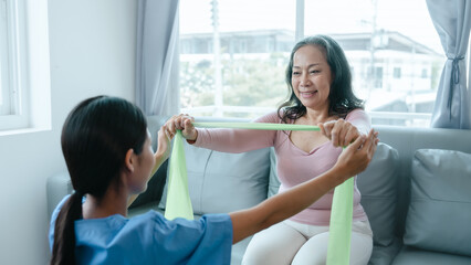 Obraz premium Asian Chinese female physiotherapist caregiver helping elderly woman exercise for recovery, prevention of osteoarthritis and osteoporosis.