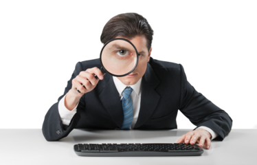 Businessman looking in a magnifying glass and working on a keyboard