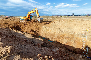 Excavator dig the trenches at a construction site. Trench for laying external sewer pipes. Sewage drainage system for a multi-story building. Digging the pit foundation