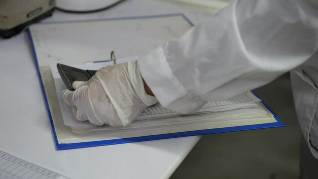 Scientist analyzing data on pocket calculator in laboratory, lab testing