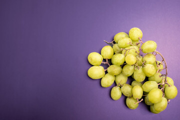 overhead shot of green grapes on purple background, grape concept