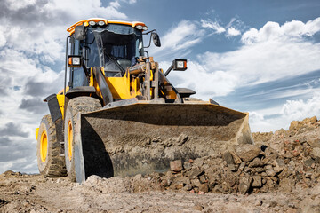 Powerful front wheel loader or bulldozer working on a quarry or construction site. earthworks in...