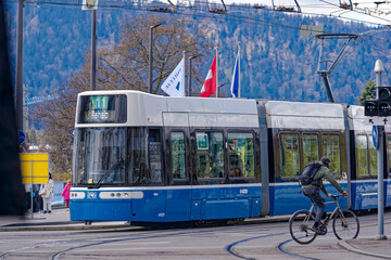 People and cyclist at town square and tram station named Bellevue at City of Zürich on a blue...