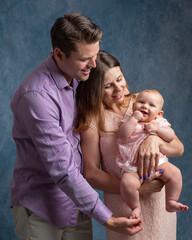Dad, mom hold their little daughter in their arms Portrait of a young family. Tenderness and love of parents.