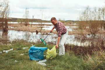 Volunteer and environmental activist cleaning dirty lake shore filled with trash.