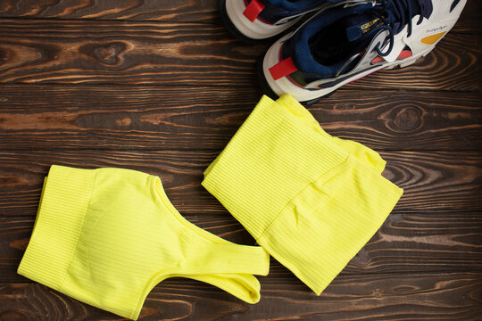 Sport shoes with sportswear on wooden table.