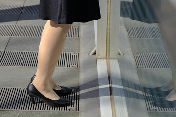 屋外で立ち止まってスマホを操作しているビジネスウーマン	