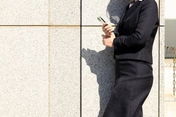屋外で立ち止まってスマホを操作しているビジネスウーマン	