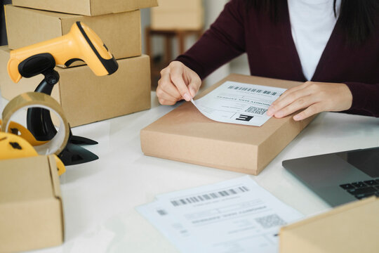 Young business owner putting shipping label on parcel.