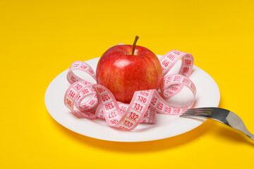 Concept of weight loss and healthy nutrition with apple and measuring tape