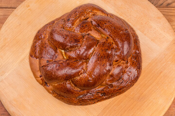 Baked sweet braided bread on a wooden surface, top view