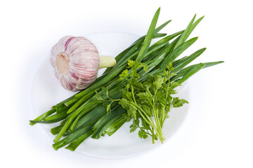 Stems and bulb of garlic on dish on white background