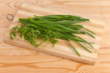 Garlic and parsley stems on cutting board on rustic table