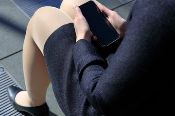 ベンチに座ってスマホを操作している女性　屋外　ビジネス