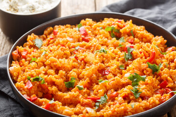 Bulgur Pilaf is a Middle Eastern dish made with vegetables and spices close-up on a plate on a wooden table. Horizontal