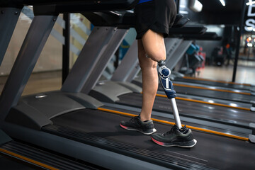 Fototapeta na wymiar Low angle view woman with prosthetic leg walking in treadmill at fitness gym