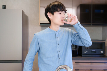 キッチンで水を飲む男性