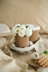 A cup of warm, warming aromatic tea, coffee, flowers nearby