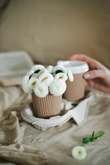 A cup of warm, warming aromatic tea, coffee, flowers nearby