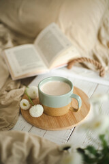 A cup of warm, warming aromatic tea, coffee, flowers nearby