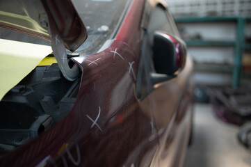 A car mechanic checks the condition of a car body to be repaired after a collision. by marking the X that need to be repaired