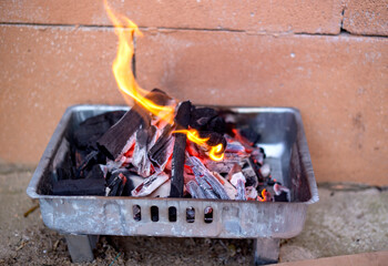 Burning charcoal in a barbecue on a brick wall background, close-up