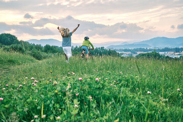 Mother teaching son to ride bicycle. Happy cute boy in helmet learn to riding a bike in park on...