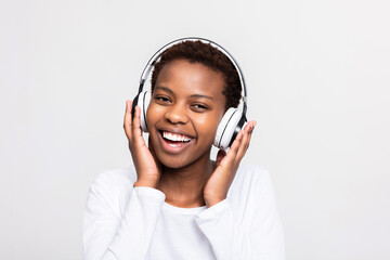 Happy young afro american woman listening to music wearing modern new headphones headset earphones advertisement banner concept over white background in studio. Emotional female.