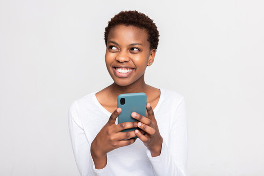 Charming African Woman With Short Haircut Holding Cellphone In Hands Chatting Messaging With Someone Boyfriend Friends Family Holding New Modern Device In Arms.