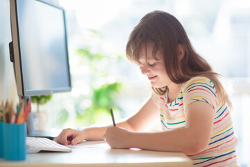 Child doing homework on computer. Online class.