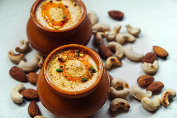 Delicious Kulfi ice cream in two clay pots on a white background with cashews and almonds. - obrazy, fototapety, plakaty