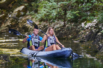 A young couple enjoying an idyllic kayak ride in the middle of a beautiful river surrounded by forest greenery