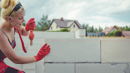 Woman using string as level in wall construction.