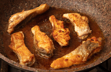 The fish is fried in a frying pan in oil. Close-up.