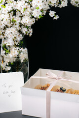 a box of cake pops on black background and white blossom