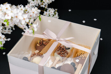 a box of cake pops on black background and white blossom