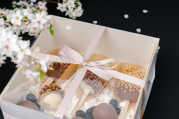 a box of cake pops on black background and white blossom