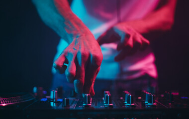 Hands of a DJ adjusting volume frequency regulators on a sound mixer. Professional disc jockey...
