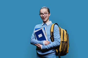 Portrait of teen girl high school student on blue studio background