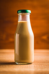 Coffee milk in glass bottle on wooden table.