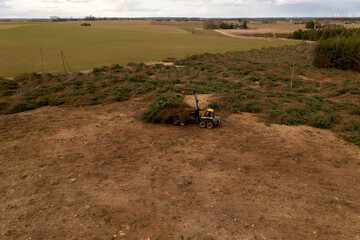 Drone photography of forestry machine piking up small trees and transporting