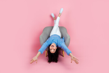 Full size portrait of satisfied girl rejoice sit chair upside down isolated on pink color background